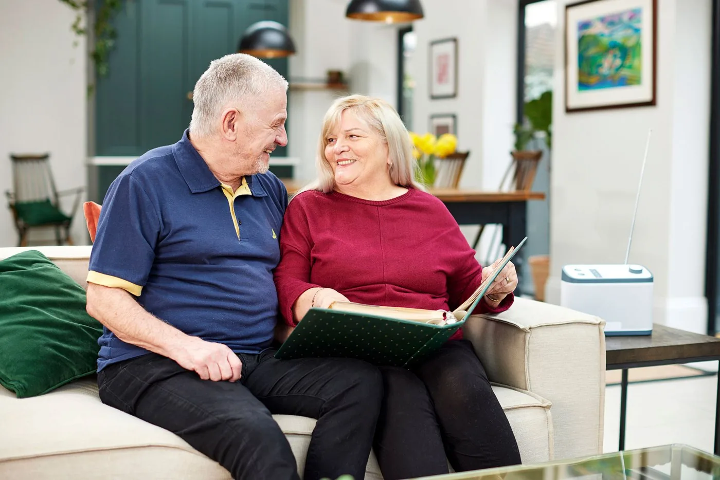 An older couple looking through a photo album together on a sofa