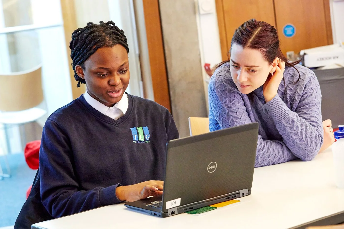 A TLG student working at a laptop alongside a mentor