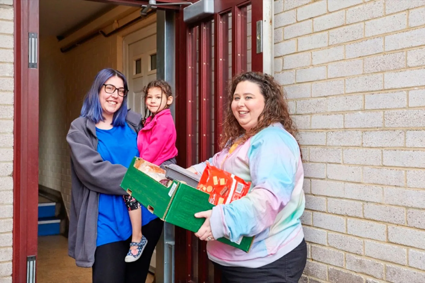 A TLG volunteer delivering a food parcel to a mother and child at their door
