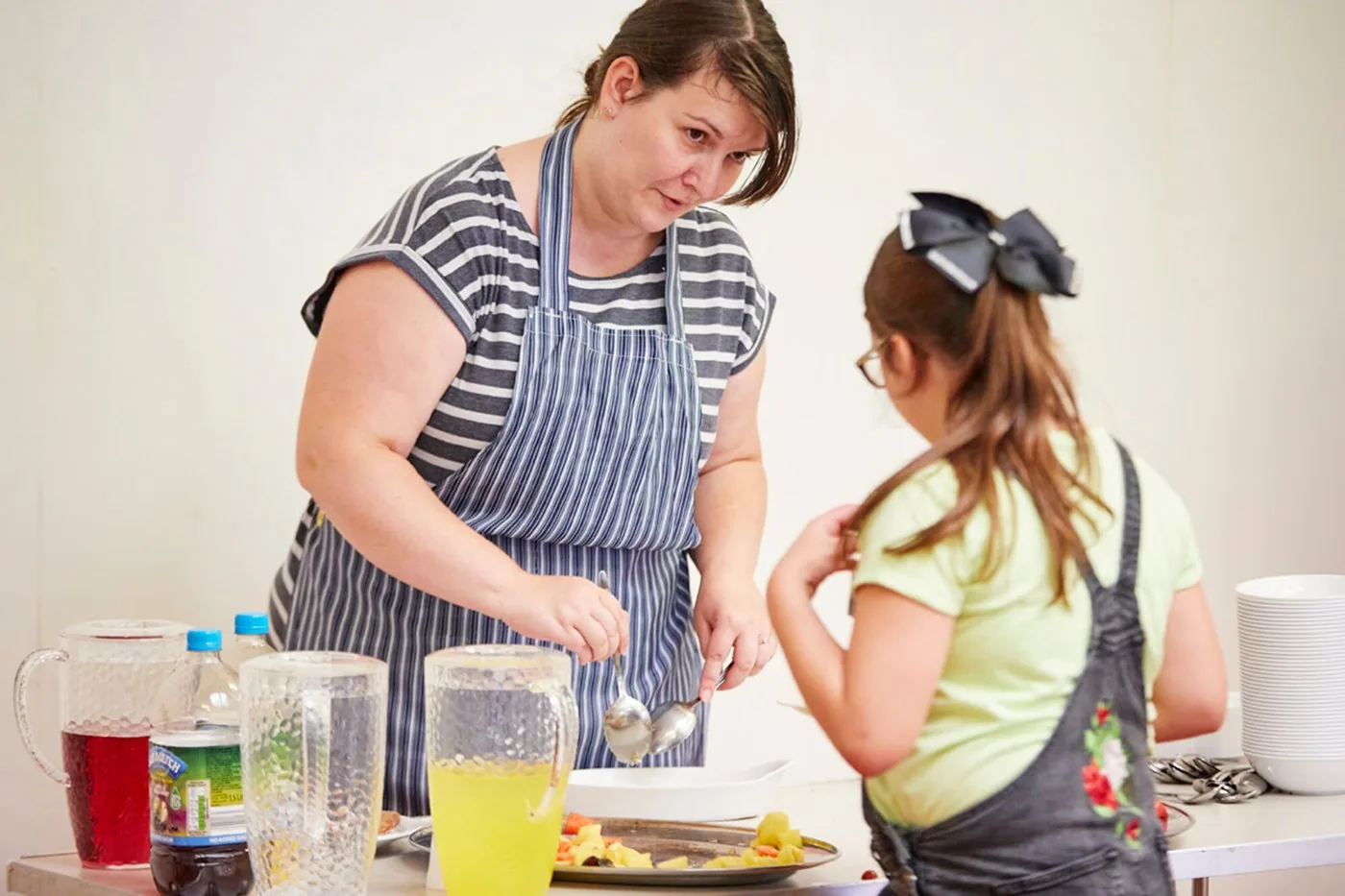 A volunteer serving food to a child at a TLG Make Lunch club